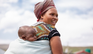 A mother carries her 4-month-old infant on her back following their well child visit in Lesotho.